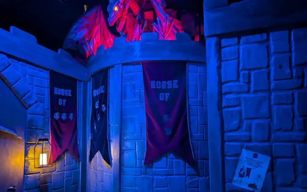 Glowing red dragon perched atop blue stone castle battlements in Swords, Stones, & Magic escape room at Huddy's Escape in Gainesville, Florida.